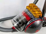 a small black and red vacuum with a yellow ball on it