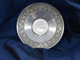 an antique silver plate with a leaf design on it on a blue cloth