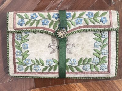 a small purse with a green ribbon and blue flowers on it