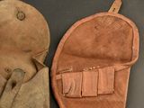 pair of leather mitts with leather handles on a black surface