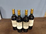 three bottles of red wine are lined up on a wooden table