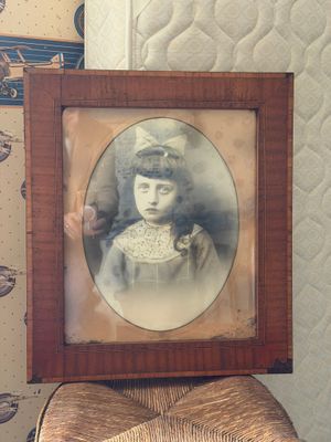 une vieille photo d'une petite fille assise sur une chaise