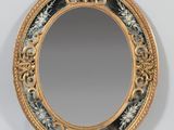 an oval mirror with a gold frame and a floral design