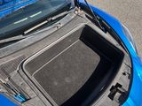 une voiture bleue dont le capot est ouvert, garée dans la rue