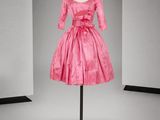 une robe rose posée sur un mannequin devant un fond gris