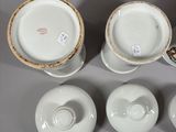 several white and gold china cups and saucers on a gray surface