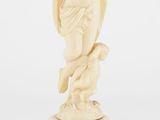 une figurine en ivoire sculpté représentant un homme tenant un oiseau sur un socle