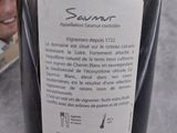a bottle of wine sitting on a table with a woman in the background