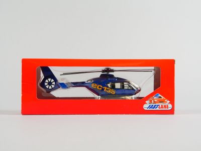 un hélicoptère jouet dans une boîte rouge posée sur une surface blanche