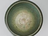 a close up of a green bowl on a white surface