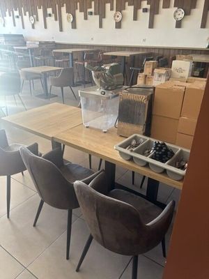 des tables et des chaises dans un restaurant, avec des cartons empilés par terre