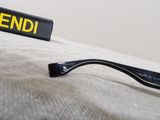 a pair of glasses sitting on a bed next to a box of fendi