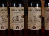 three bottles of red wine are lined up on a shelf