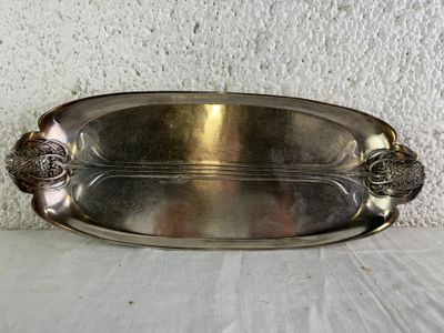 a silver plate on a table with a white wall in the background