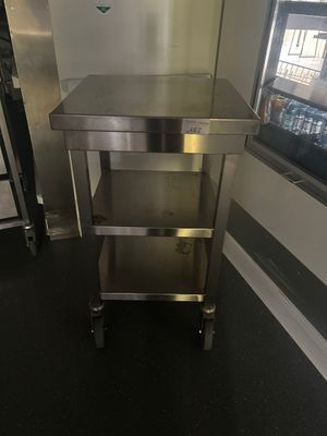 une table en acier inoxydable dans une cuisine, avec un réfrigérateur en arrière-plan