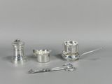 trois objets en argent posés sur une table, à côté d'une paire de ciseaux