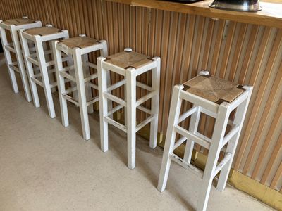 quatre tabourets blancs devant un bar équipé d'une télévision