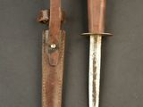 two knives with leather sheaths on a black surface