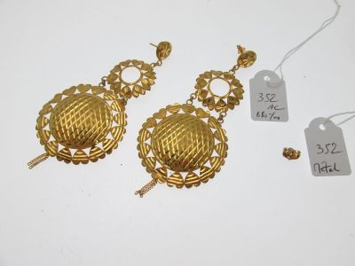 deux paires de boucles d'oreilles en or et une étiquette de prix posée sur une surface blanche
