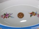 a blue bowl with flowers on it and a gold button