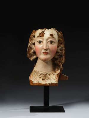 a carved head of a woman wearing a brown dress