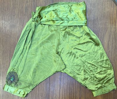 une photo d'un pantalon vert posé sur un parquet