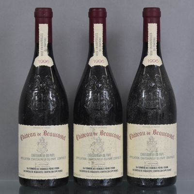 Trois bouteilles de vin rouge sont alignées sur une table en verre
