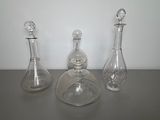 three glass decanters sitting on a table next to each other