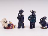 four ceramic figurines of people with hats and clothes