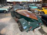 many old cars parked in a garage with a wooden boat on the back