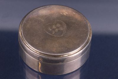 un récipient en argent muni d'un couvercle en argent, posé sur une table