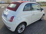 a small white car with a red top parked in a parking lot
