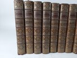 several old books are lined up in a row on a white surface