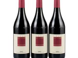 three bottles of red wine sitting next to each other on a white surface