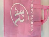 the pink bag has a white logo on it and is hanging on a wall