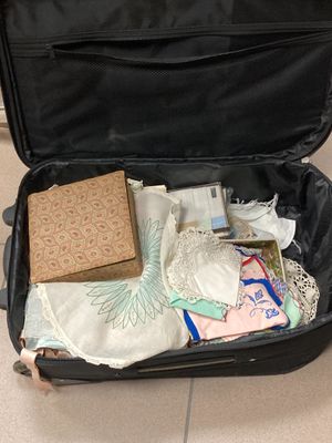 une valise noire remplie d'objets, posée sur un sol carrelé