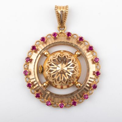 a close up of a gold pendant with pink stones on a white background