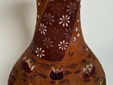 a brown vase with flowers on it sitting on a white surface