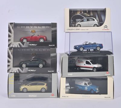 Quatre modèles différents de voitures sont rangés dans des cartons sur une surface blanche.
