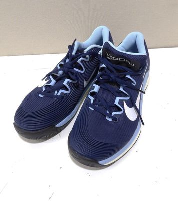 des baskets bleues et blanches posées sur une surface blanche, avec un mur en arrière-plan