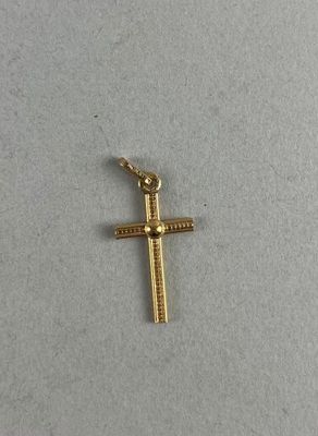 a small gold cross on a white surface with a chain