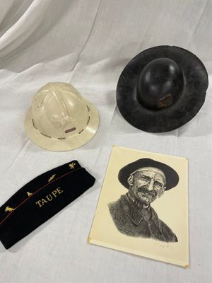 deux chapeaux et une carte posés sur un tissu blanc, avec la photo d'un homme coiffé d'un chapeau