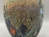 a black vase with a multicolored design sitting on a white surface