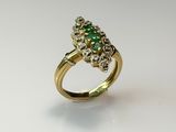 gros plan d'une bague en or avec une pierre verte