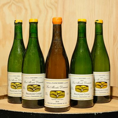 several bottles of wine are lined up on a wooden barrel