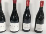 four bottles of wine are lined up on a white surface