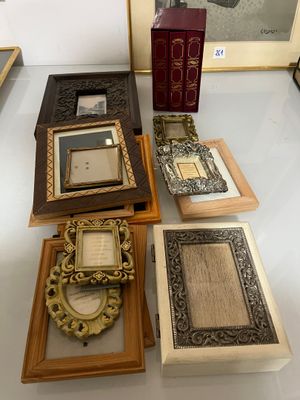 many different frames on the table with pictures on the wall