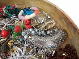 a wooden bowl filled with assorted jewelry and bracelets