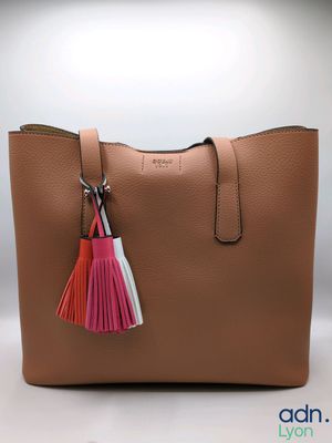 a tan purse with a pink tassel hanging from the handle