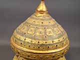an ornate gold plated box with a domed top on a wooden stand